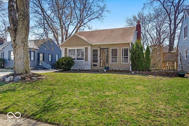 view of front of home featuring entry steps, a front yard, roof with shingles, and a chimney