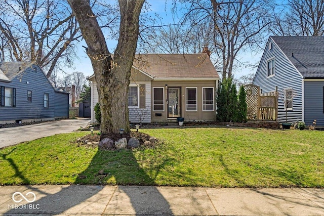 view of front of home with a chimney, a front lawn, and roof with shingles