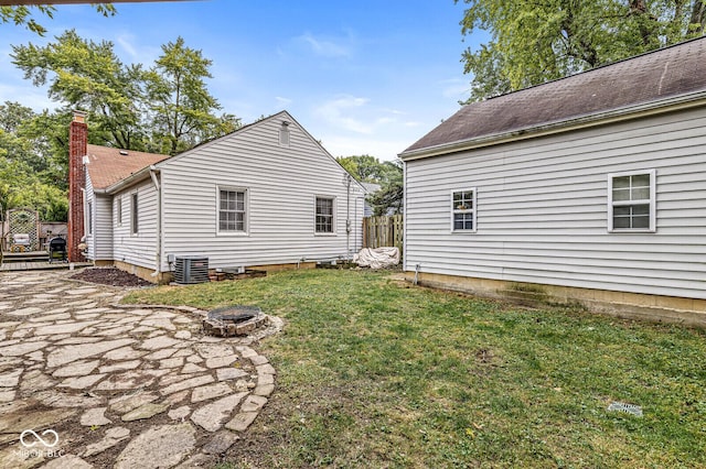 exterior space featuring a chimney, central AC unit, a lawn, and an outdoor fire pit