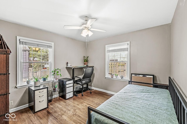 bedroom with multiple windows, wood finished floors, and baseboards