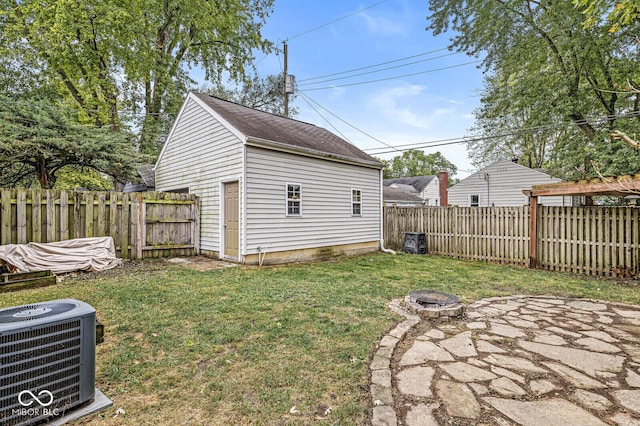 view of yard with an outbuilding, cooling unit, an outdoor fire pit, and a fenced backyard