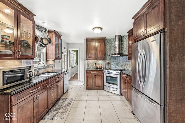 kitchen featuring light tile patterned flooring, a sink, appliances with stainless steel finishes, wall chimney exhaust hood, and tasteful backsplash