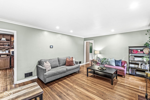 living area with visible vents, wood-type flooring, baseboards, and ornamental molding