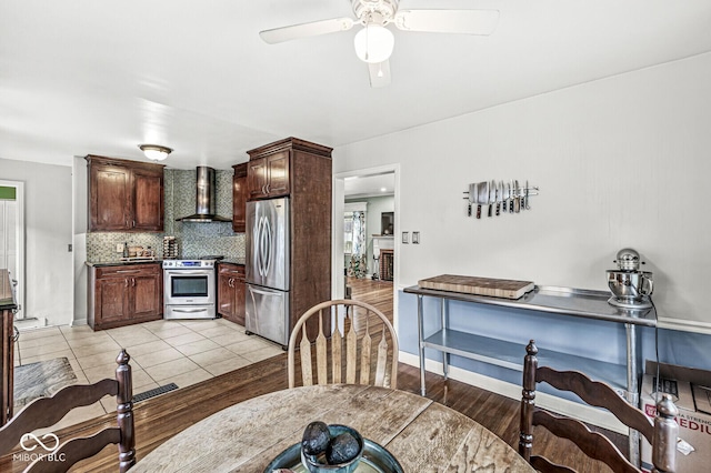 kitchen featuring a ceiling fan, tasteful backsplash, dark brown cabinetry, appliances with stainless steel finishes, and wall chimney exhaust hood