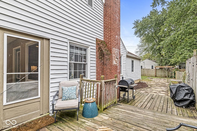 wooden terrace featuring fence and a grill