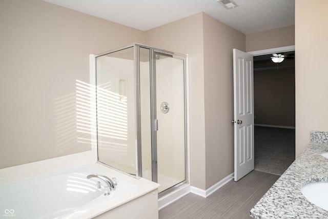 bathroom featuring visible vents, a garden tub, a shower stall, baseboards, and vanity