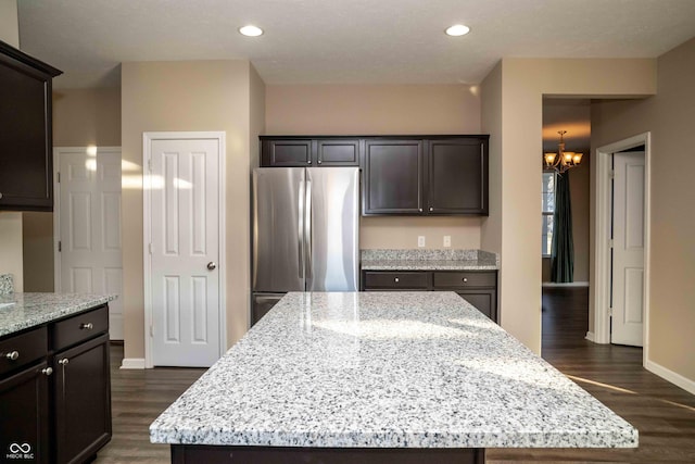 kitchen with light stone countertops, a chandelier, recessed lighting, freestanding refrigerator, and dark wood-style flooring