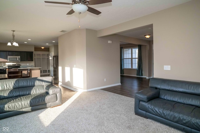 living room featuring dark colored carpet, baseboards, recessed lighting, and ceiling fan with notable chandelier