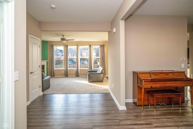 foyer with a glass covered fireplace, wood finished floors, a ceiling fan, and baseboards