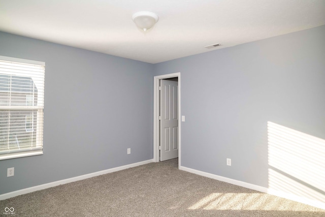 empty room featuring visible vents, baseboards, and carpet floors