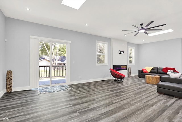 living area featuring recessed lighting, baseboards, wood finished floors, and a skylight