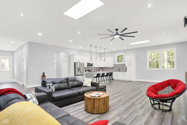 living room featuring a wealth of natural light, a skylight, and light wood-type flooring