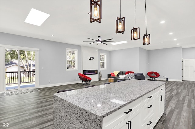 kitchen with baseboards, open floor plan, and a skylight