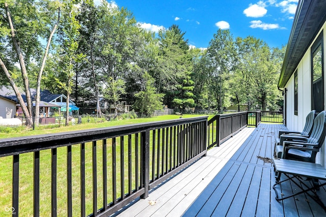 wooden terrace featuring a lawn and fence