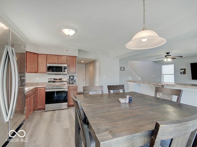 dining space with stairway, light wood-style flooring, visible vents, and ceiling fan