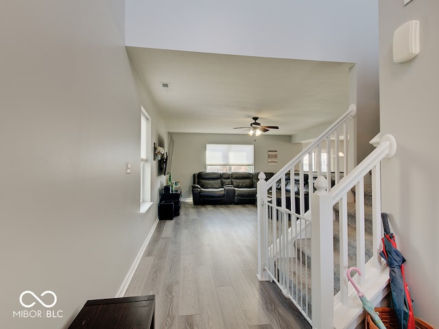 stairs with baseboards, wood finished floors, visible vents, and ceiling fan