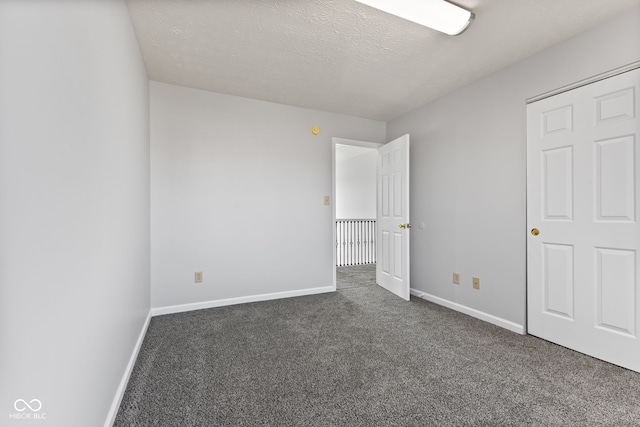 unfurnished bedroom with carpet flooring, a textured ceiling, and baseboards