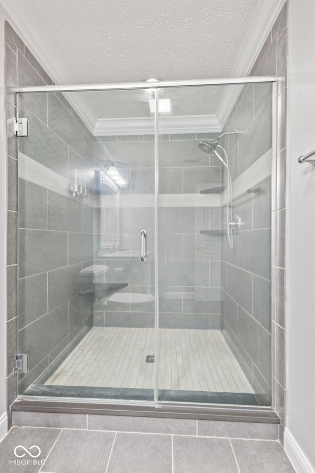 bathroom with a textured ceiling, a shower stall, and crown molding