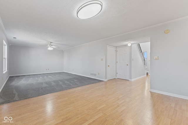 empty room with visible vents, a ceiling fan, a textured ceiling, wood finished floors, and crown molding