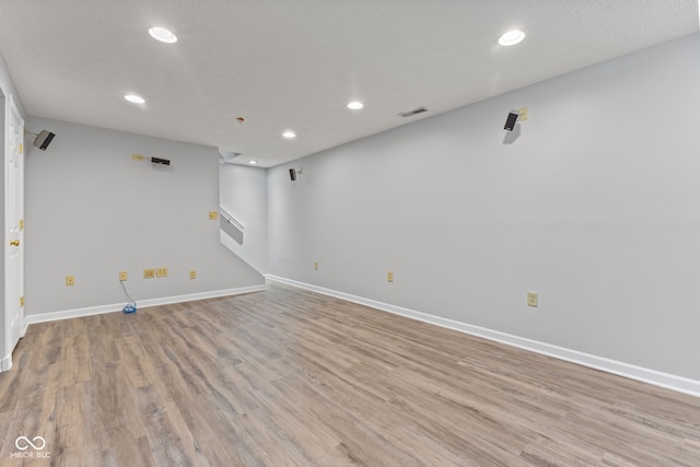 empty room featuring visible vents, baseboards, light wood-type flooring, stairs, and recessed lighting