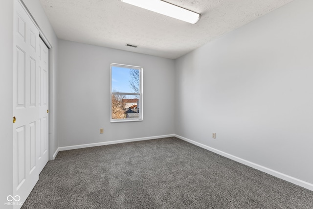 unfurnished bedroom with a closet, a textured ceiling, baseboards, and carpet floors