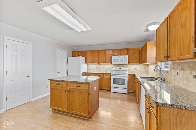 kitchen featuring white appliances, light wood finished floors, stone countertops, a sink, and brown cabinets