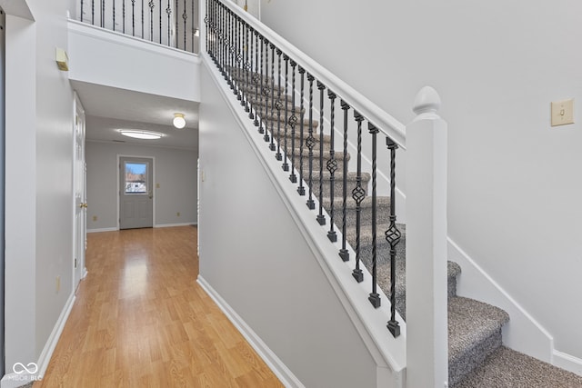 staircase with a towering ceiling, baseboards, and wood finished floors