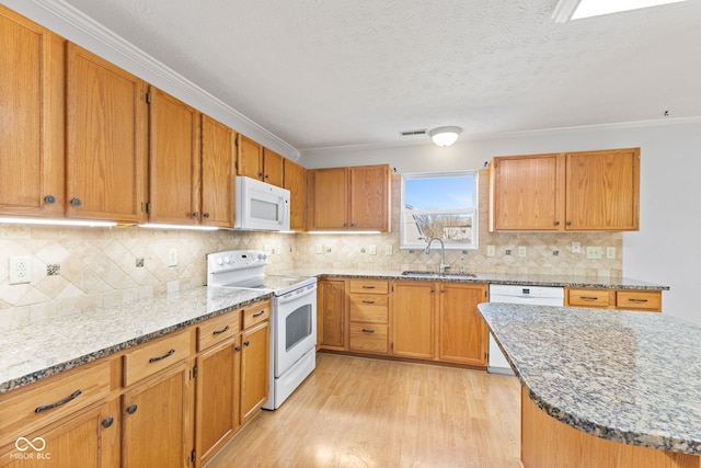 kitchen with visible vents, a sink, light stone counters, white appliances, and light wood-style floors