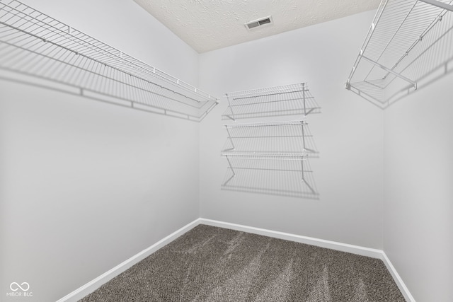 walk in closet with visible vents and dark colored carpet