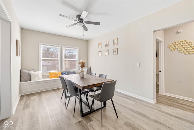 dining space with baseboards, light wood-style flooring, and a ceiling fan