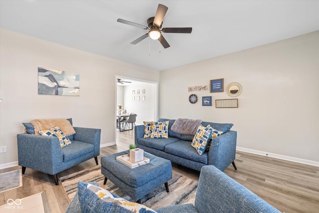 living room with ceiling fan, baseboards, and wood finished floors