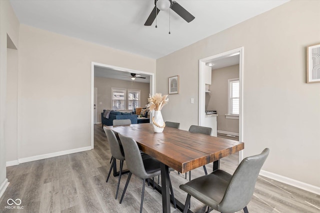 dining area with light wood finished floors, ceiling fan, and baseboards