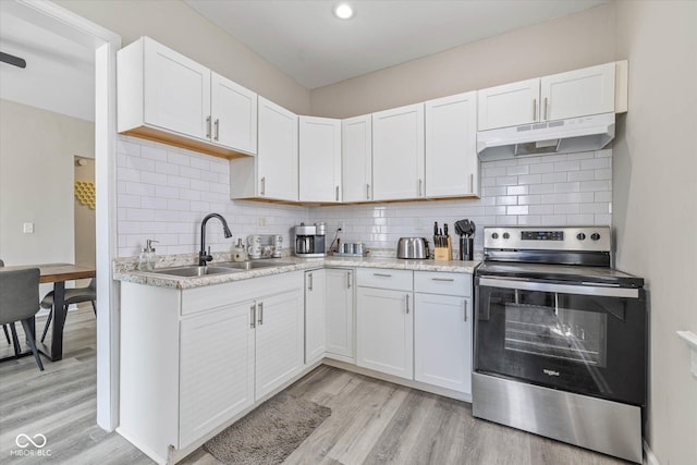 kitchen featuring under cabinet range hood, stainless steel electric range oven, light wood finished floors, and light countertops