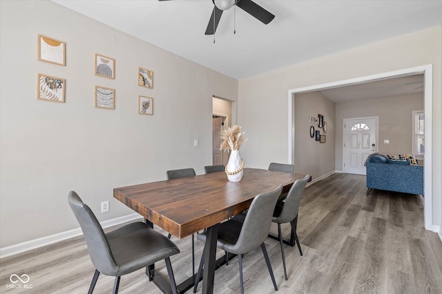 dining area with light wood-style flooring, a ceiling fan, and baseboards