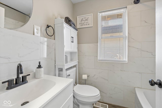 full bath with visible vents, toilet, tile walls, and vanity