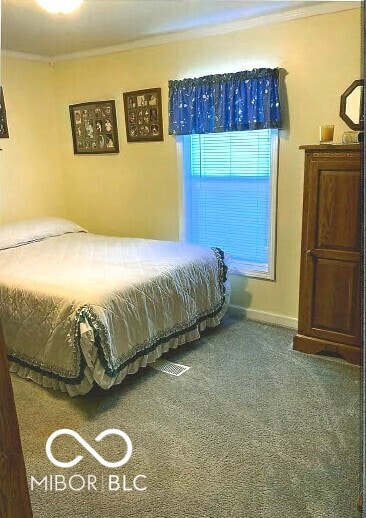 bedroom featuring baseboards, crown molding, and carpet