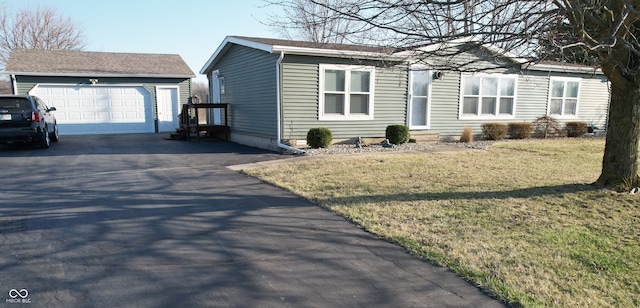 view of front of house featuring entry steps, a front lawn, a garage, and driveway