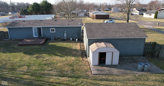 rear view of house with a lawn, a deck, a fenced backyard, an outdoor structure, and a storage unit