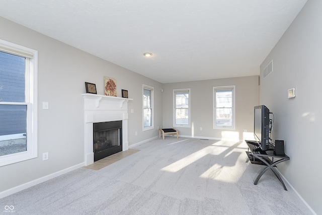 living room with visible vents, baseboards, light colored carpet, and a fireplace with flush hearth