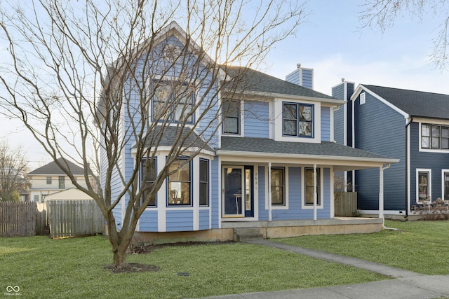 view of front of property featuring a front yard, fence, covered porch, and a shingled roof