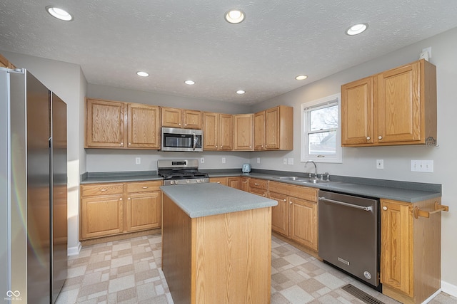 kitchen with a center island, light floors, recessed lighting, appliances with stainless steel finishes, and a sink