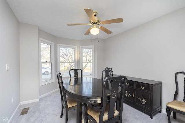 dining room featuring light carpet, visible vents, ceiling fan, and baseboards