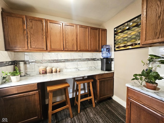 kitchen featuring brown cabinetry, decorative backsplash, and baseboards