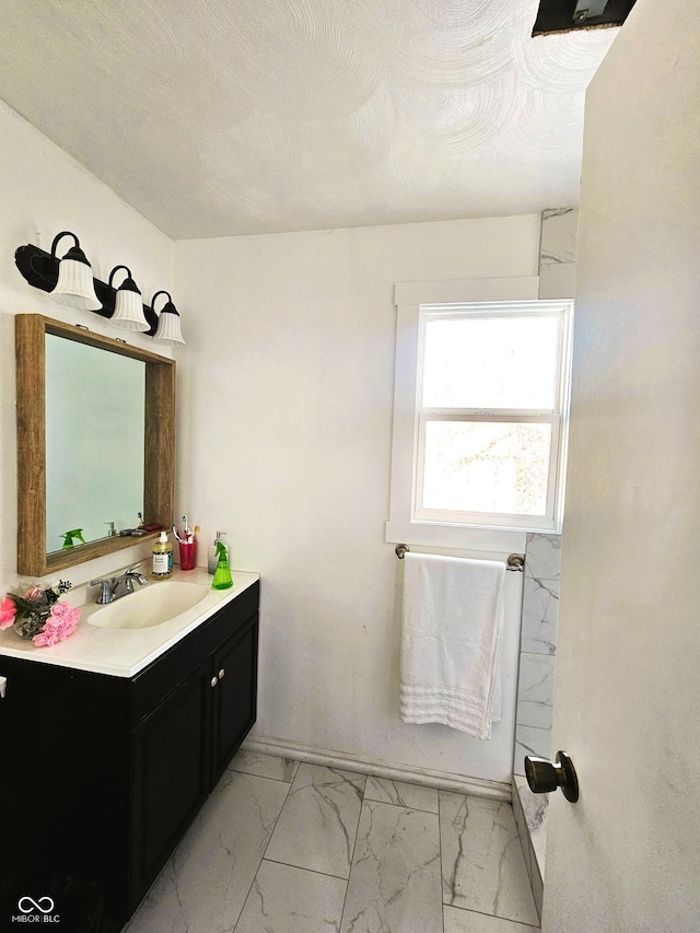 bathroom with a textured ceiling, marble finish floor, and vanity