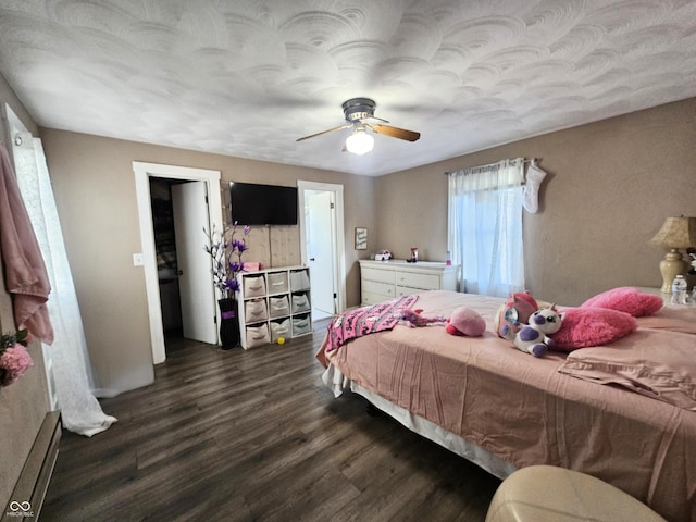 bedroom with baseboard heating, ceiling fan, and dark wood-style flooring