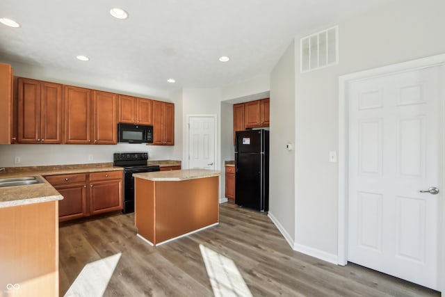 kitchen featuring wood finished floors, visible vents, a kitchen island, recessed lighting, and black appliances