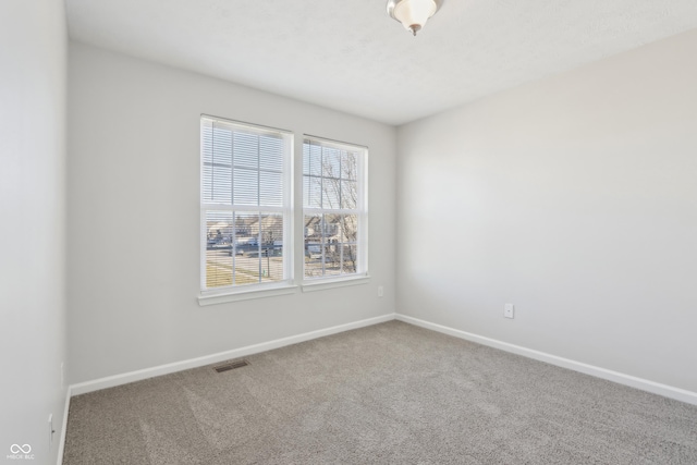 carpeted spare room featuring baseboards and visible vents