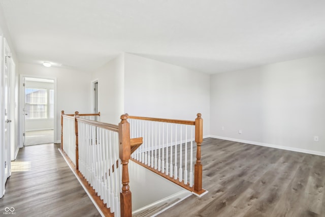 hallway featuring an upstairs landing, baseboards, and wood finished floors