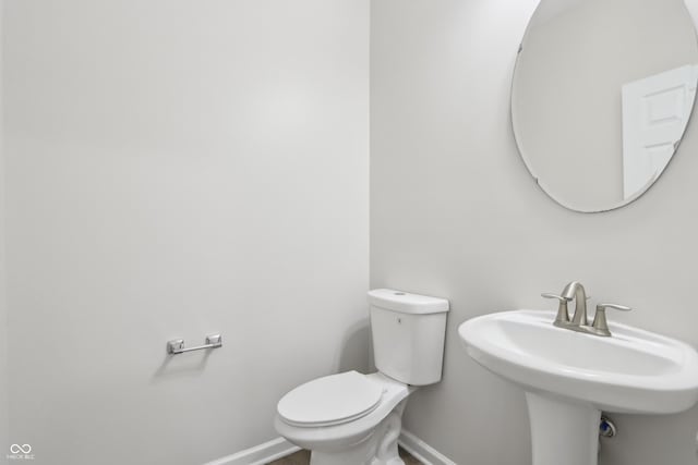 bathroom featuring toilet, baseboards, and a sink