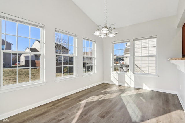 unfurnished dining area with an inviting chandelier, high vaulted ceiling, baseboards, and wood finished floors